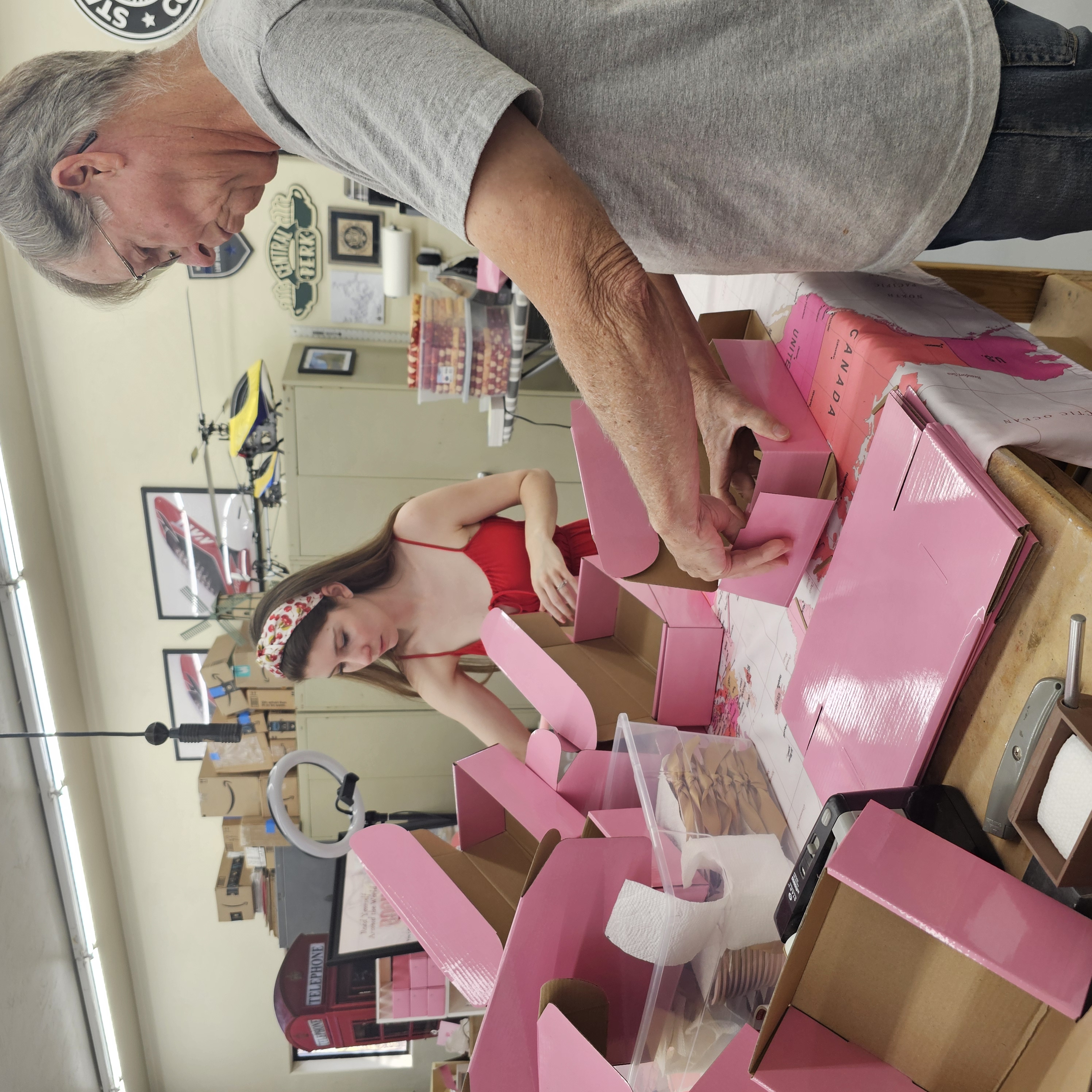 Sarah and her stepdad are shown packing a stack of pink boxes.