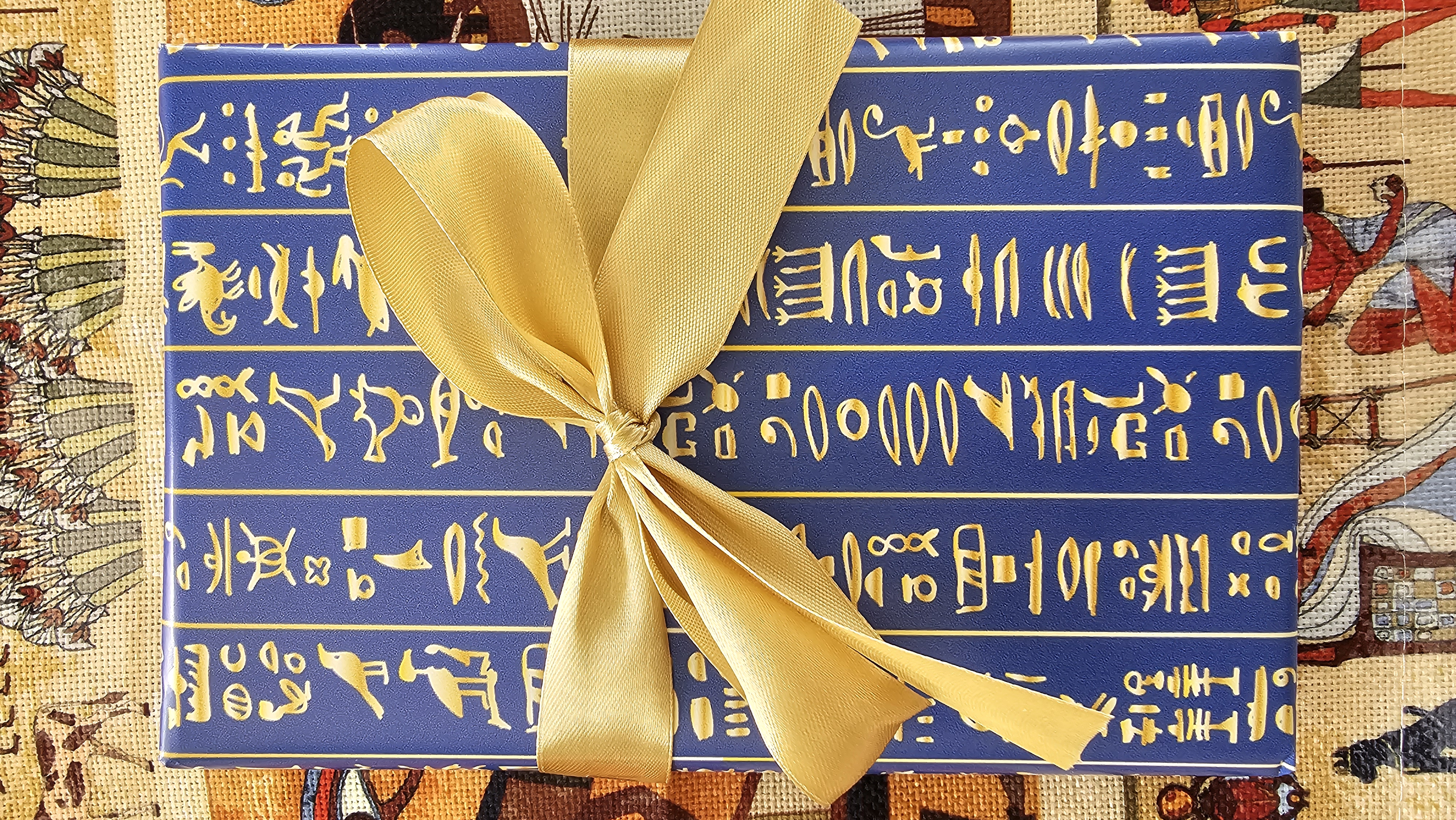 Blue and gold hieroglyphic wrapped book  with a gold bow
