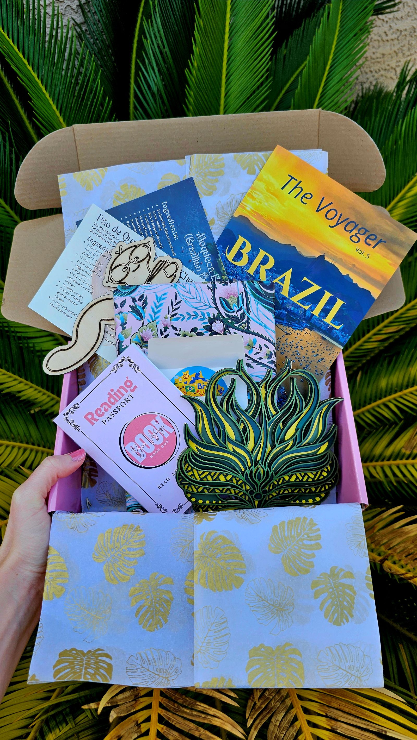 Brazil book box with a travel guide, recipes, bookmark, reading passport, mask, and novel.
