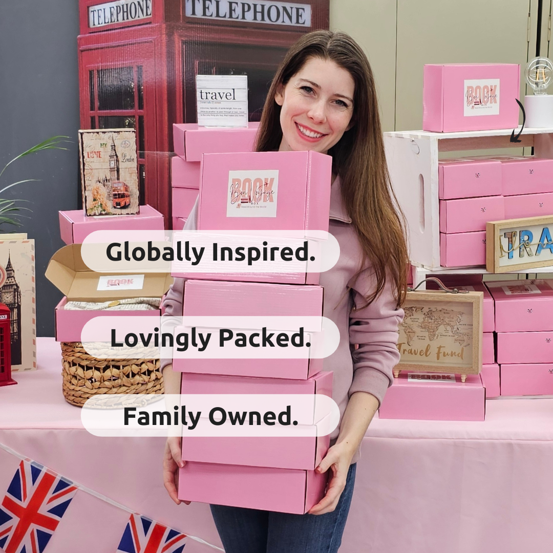 Owner holds a stack of pink boxes with the words "globally inspired, lovingly packed, and family owned" in front of the boxes.