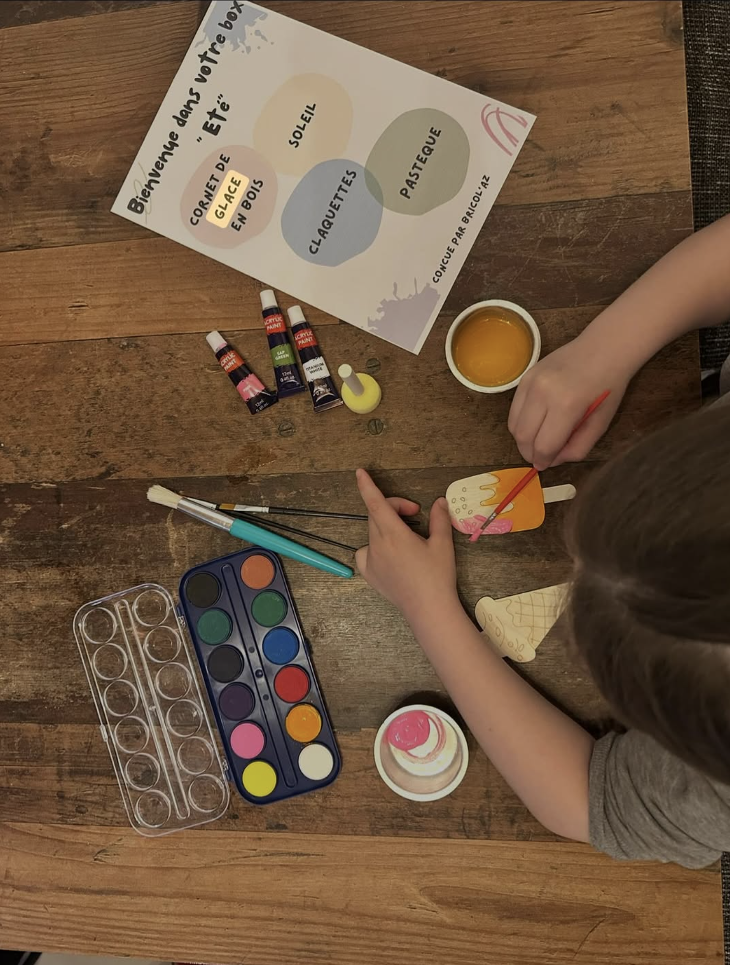 Un enfant peint une création avec une palette de couleurs Bricol’AZ