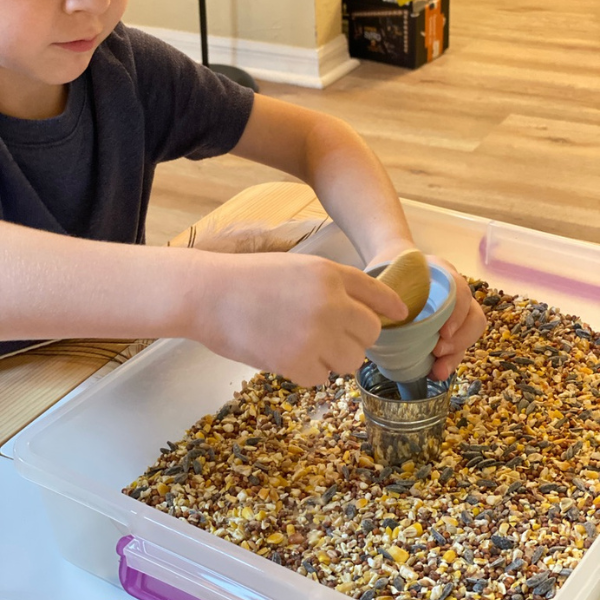 scooping bird seed for sensory play