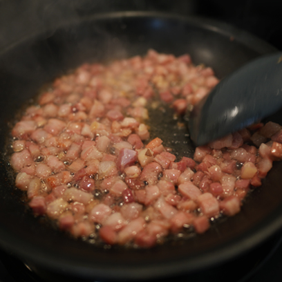 Crisping pancetta in a pan.
