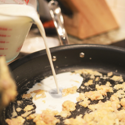 Adding milk to the sauce pan with the roux.