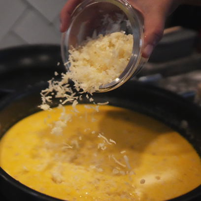 Adding cheese to the sauce pan.