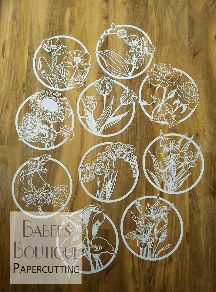 A selection of small, delicate, round paper cut-outs of various flowers