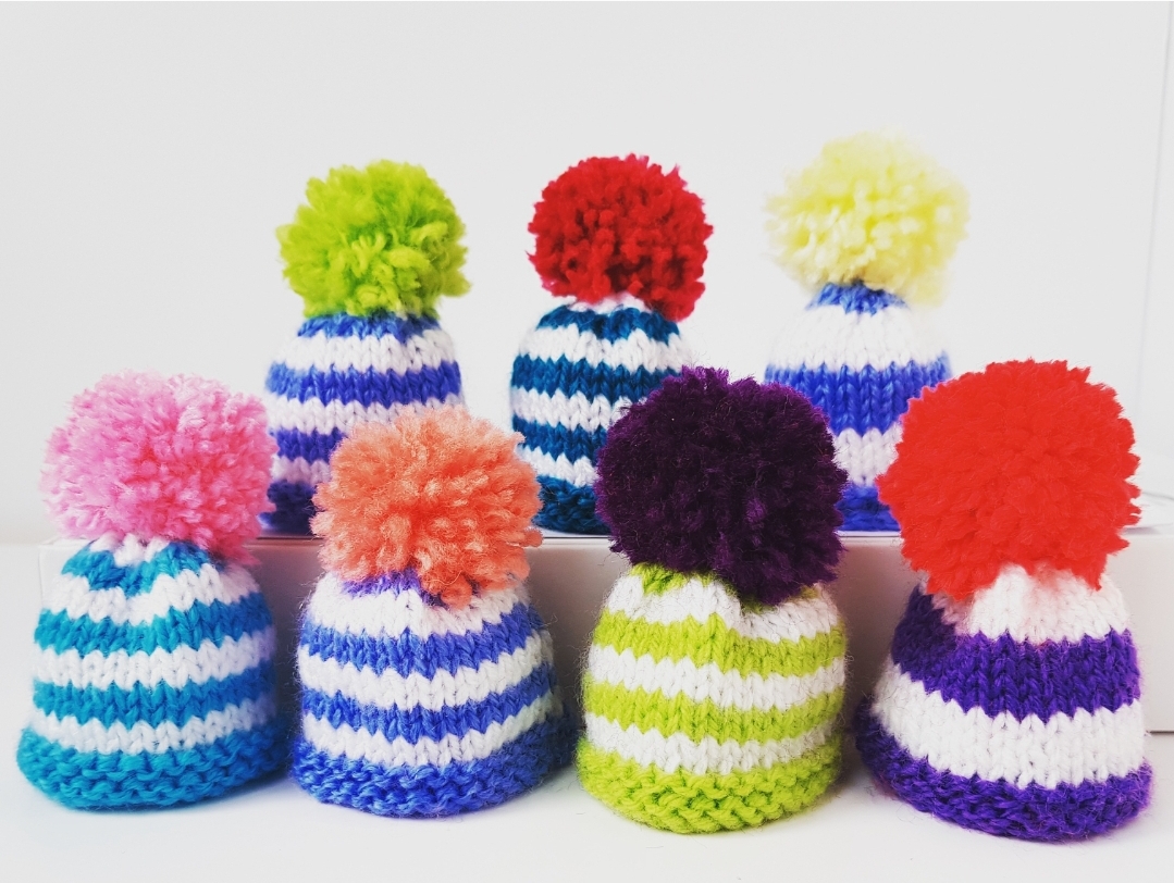 Little knitted striped hats with pompoms