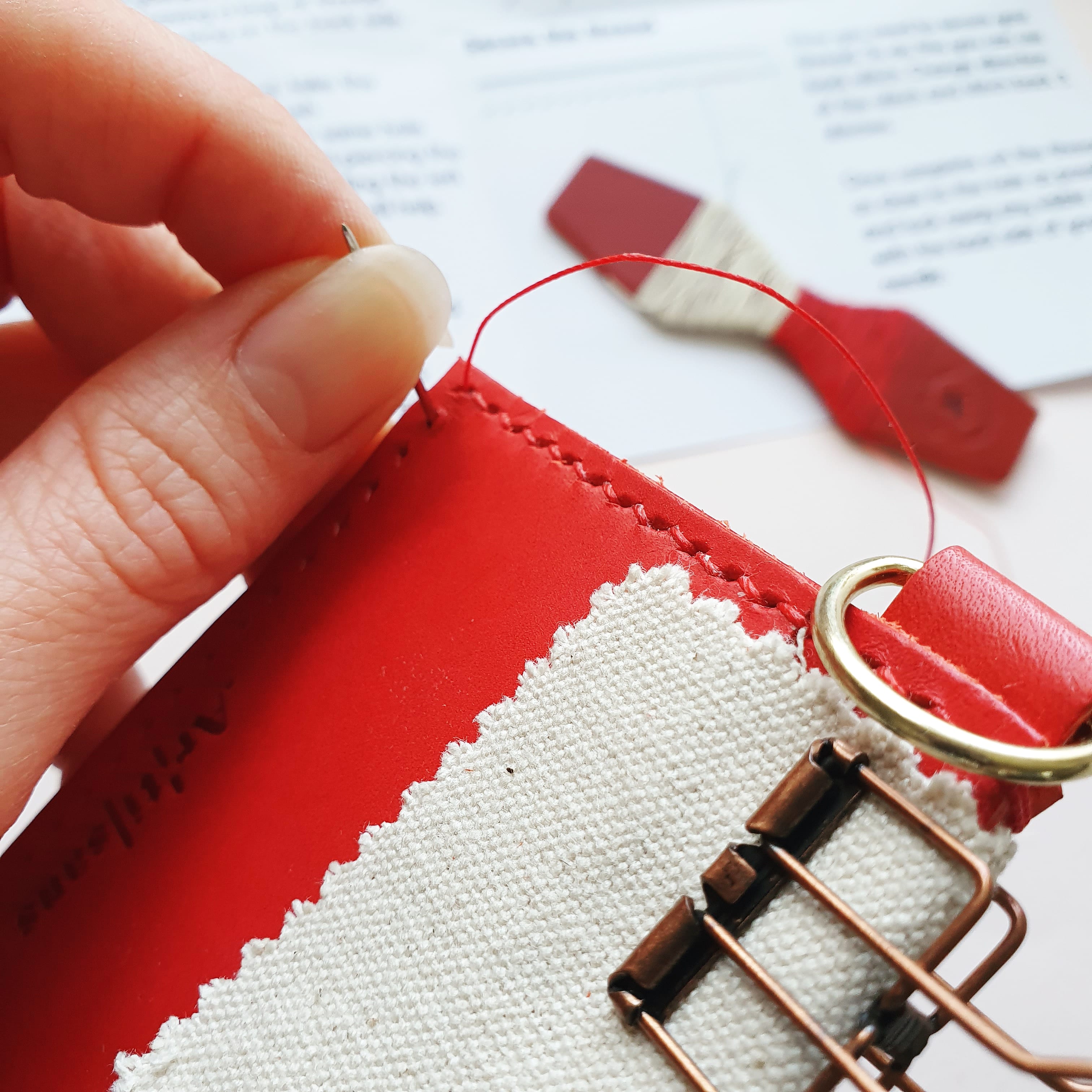 Hand stitching a red leather card holder with red thread