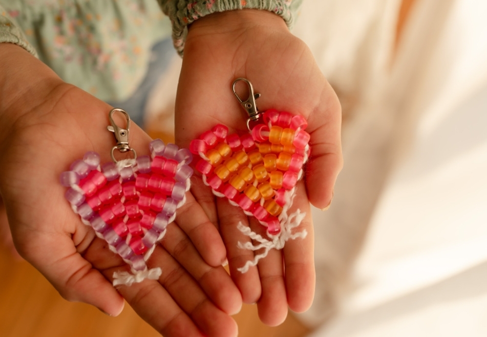 child's hands holding a beaded heart keychain