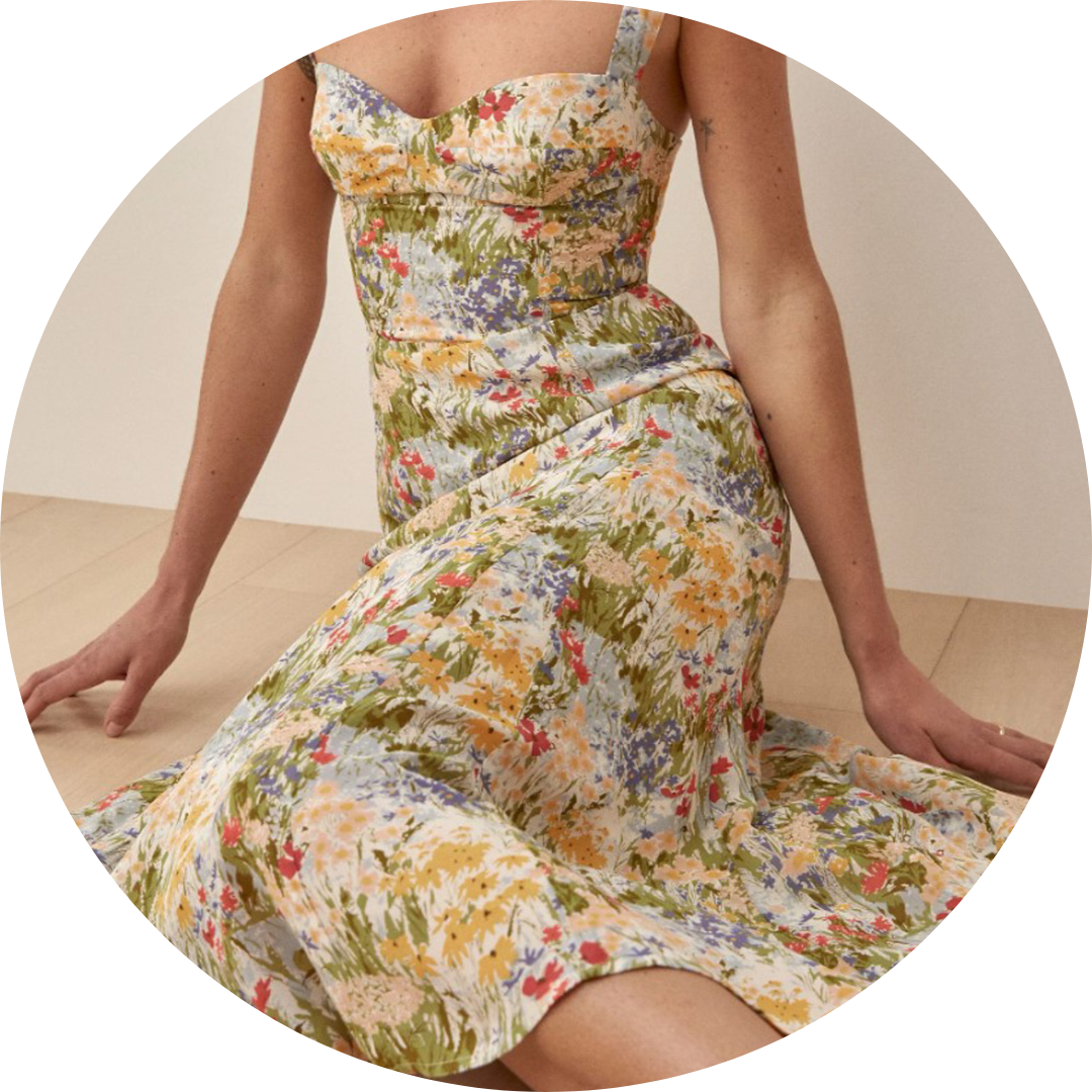 person sitting on a floor wearing flowy dress with floral pattern and thin straps