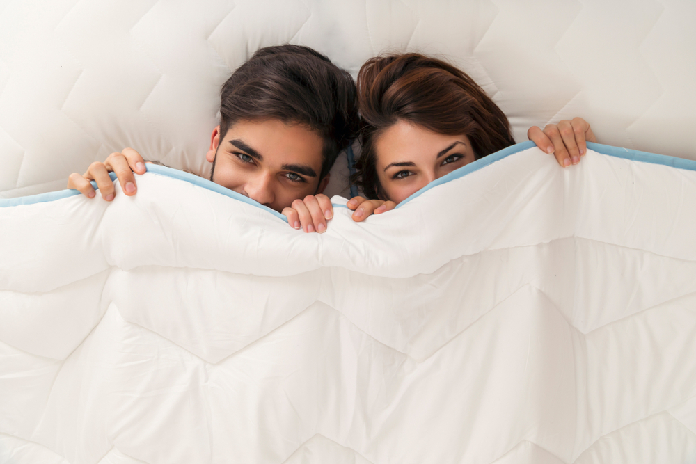 man and woman under the blanket with just eyes showing