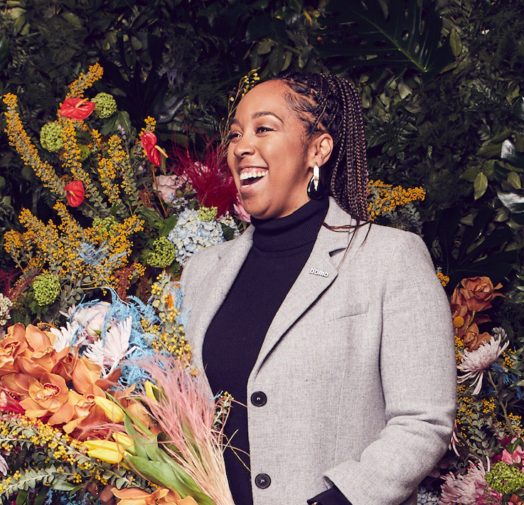 Joyous Black woman entrepreneur with flowers.