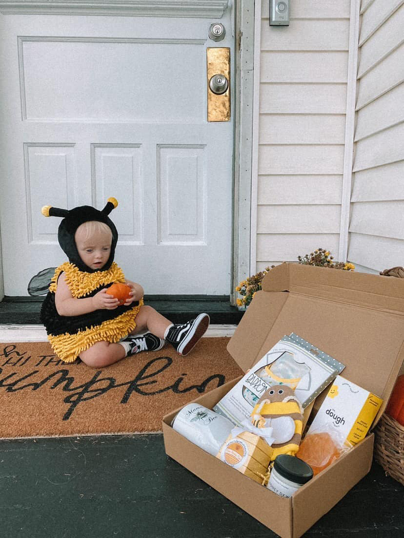 little boy playing in bee costume next to his subscription box for mom and baby