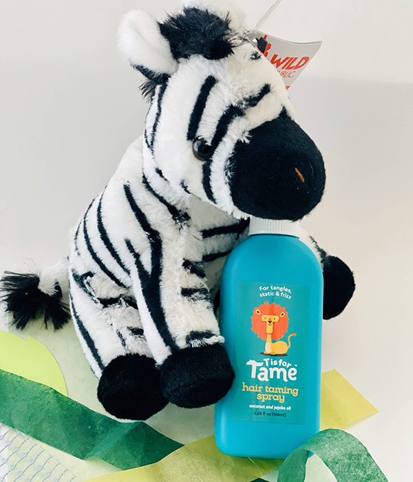 zebra animal plushie holding a bottle of baby hair taming spray