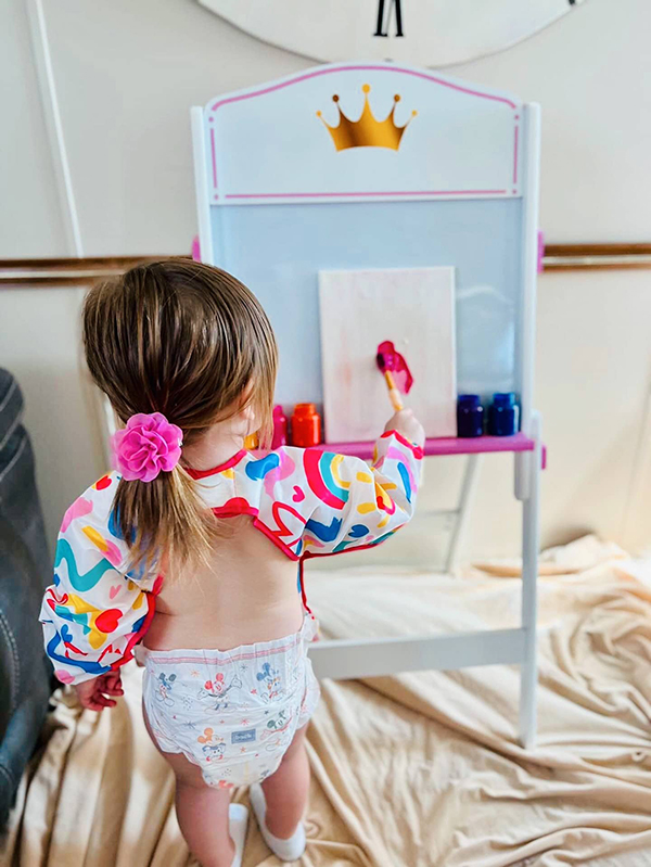 little kid painting in an art apron