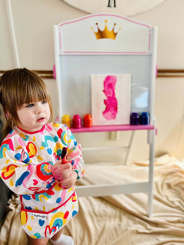 toddler girl painting in an art apron