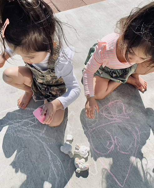 little girls drawing with sidewalk chalk