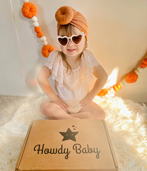 toddler girl holding the Howdy Baby childrens subscription box