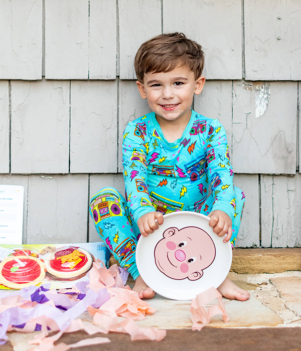 little boy holding a funny face snack plate from September 2023 Howdy Baby childrens subscription boxes