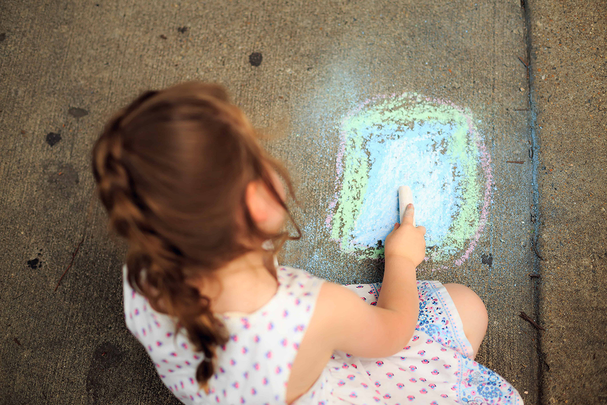 little girl drawing with sidewalk chalk