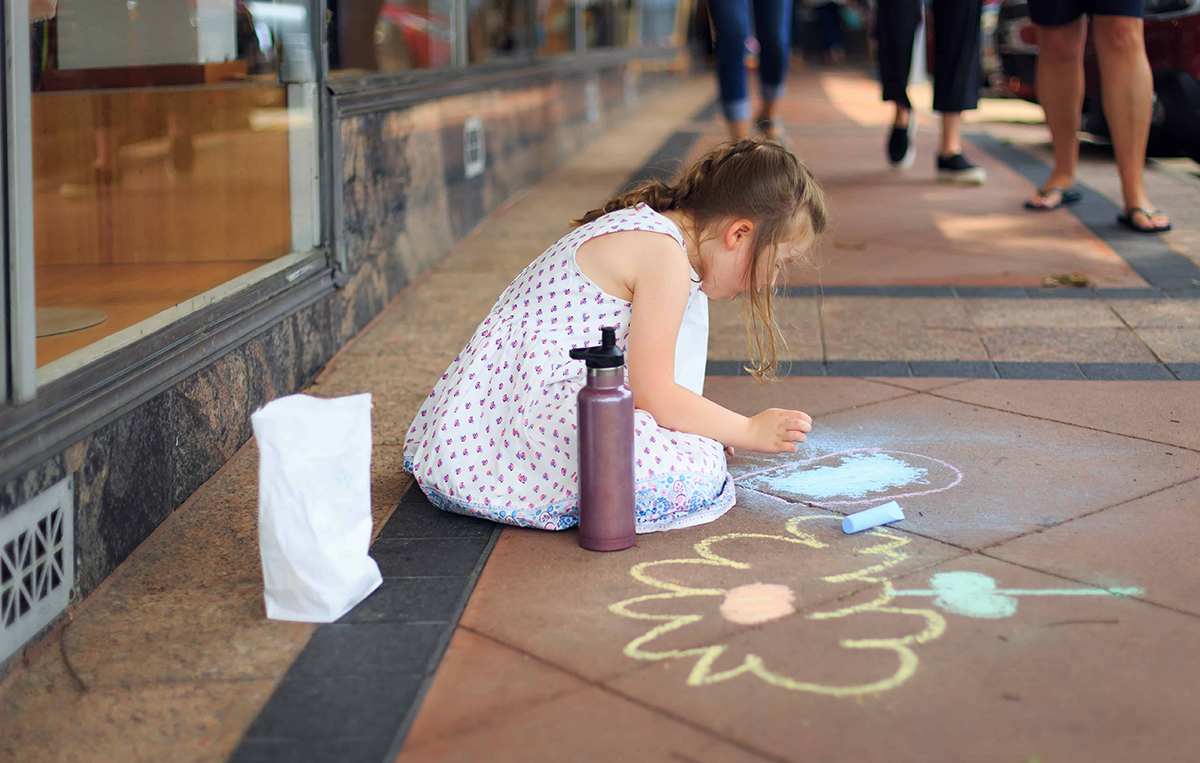 little girl playing games with sidewalk chalk outside
