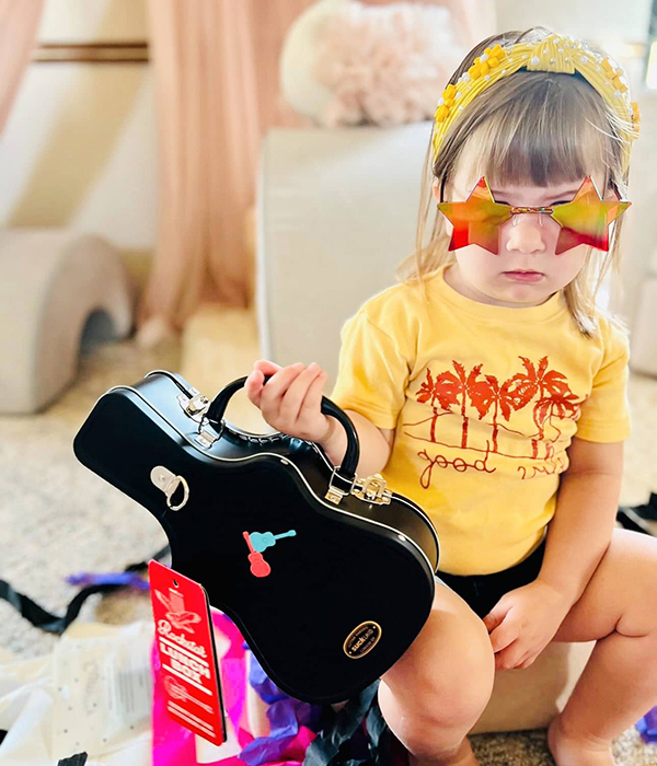 toddler girl holding a guitar shaped lunch box