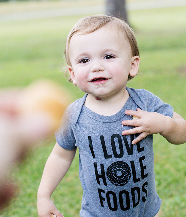 toddler wearing a grey hole foods donut onesie