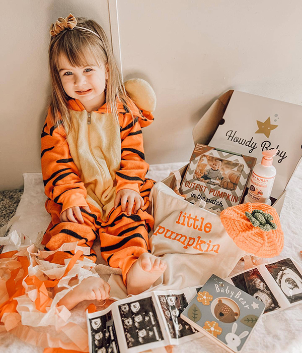 little girl sitting next to the pumpkin themed Howdy Baby subscription box