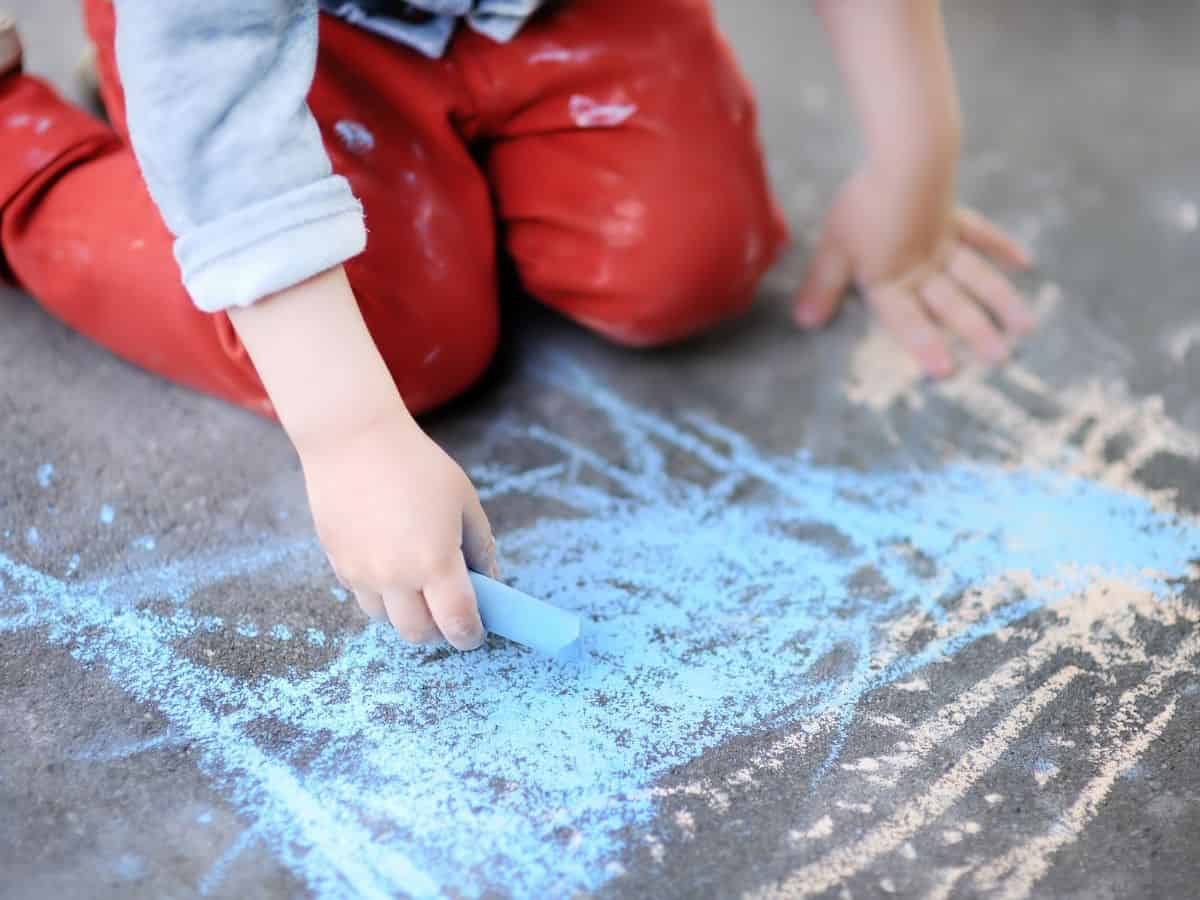 toddler boy drawing with sidewalk chalk