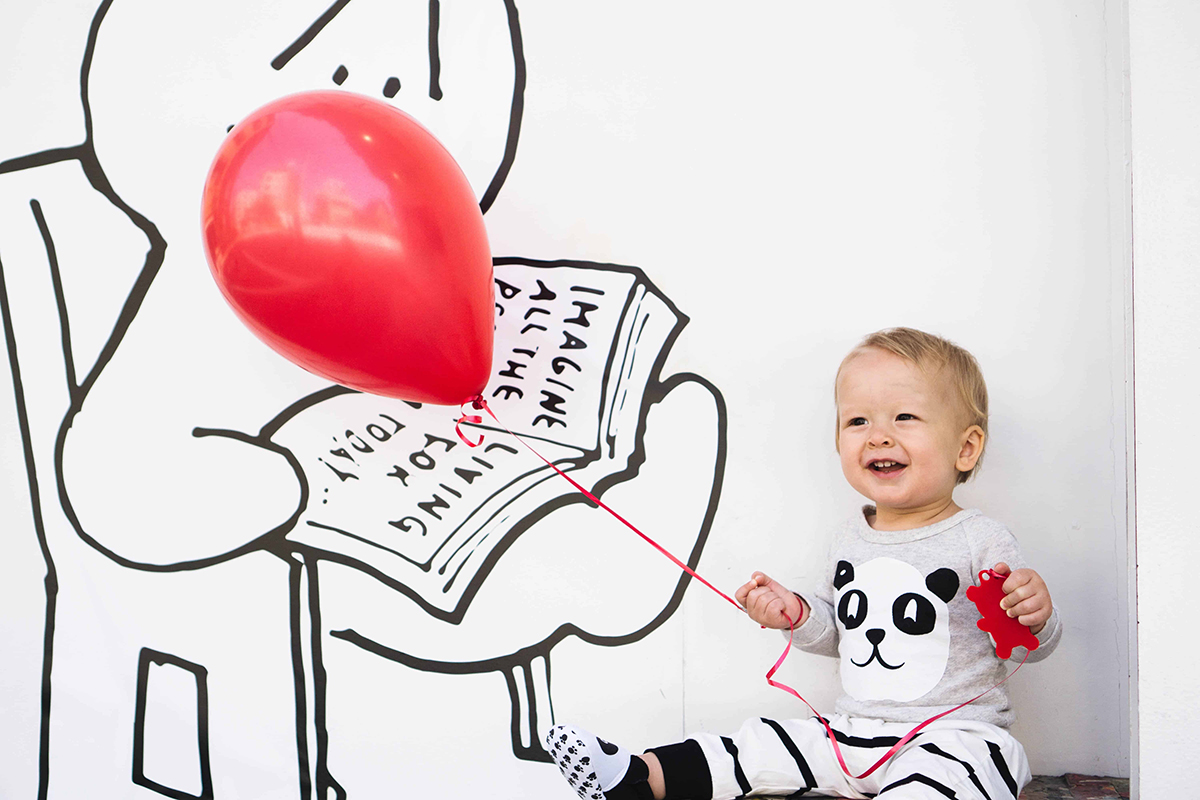 baby holding red balloon independently