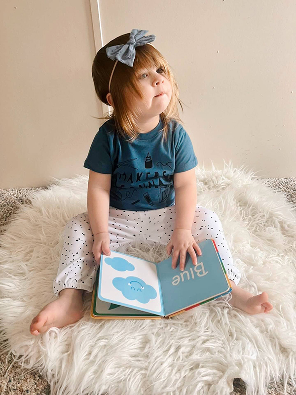 infant wearing white baby pants reading a book