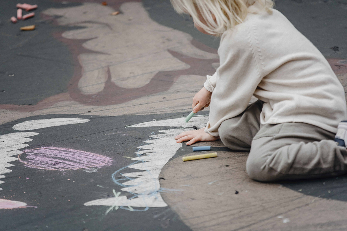 kid drawing with chalk outside