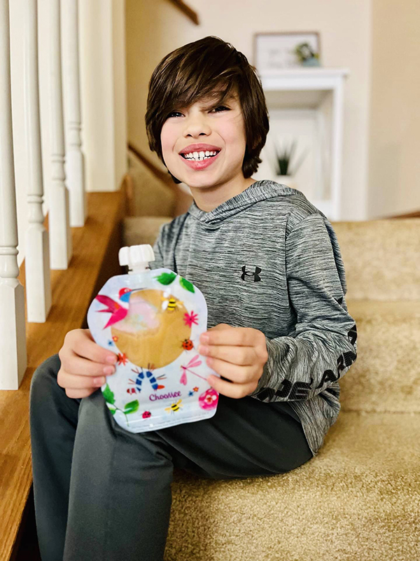 boy holding reusable food pouch from the April 2023 Howdy Baby kids box