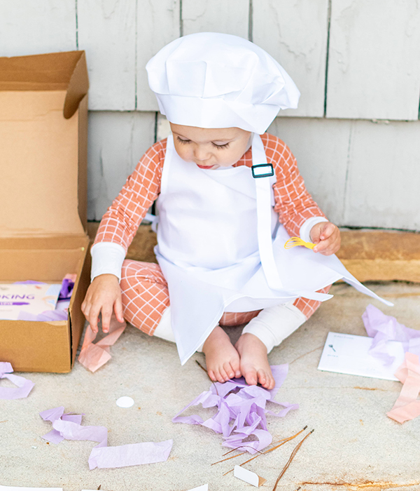 toddler wearing a chefs hat and apron from the September 2023 Howdy Kids cooking subscription box