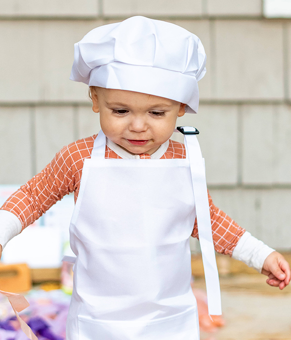 toddler wearing a chefs hat and apron from the September 2023 Howdy Kids cooking subscription box