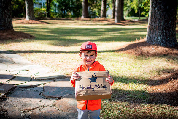 little boy holding the November 2023 Howdy Baby subscription box