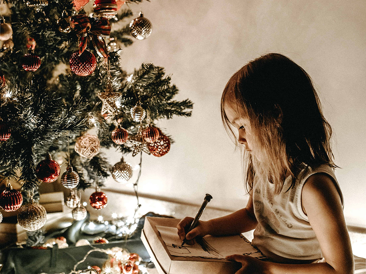 little girl coloring near Christmas tree