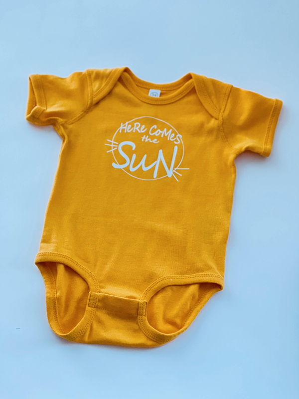 Here Comes The Sun baby onesie from the April 2023 Howdy Baby maternity subscription box