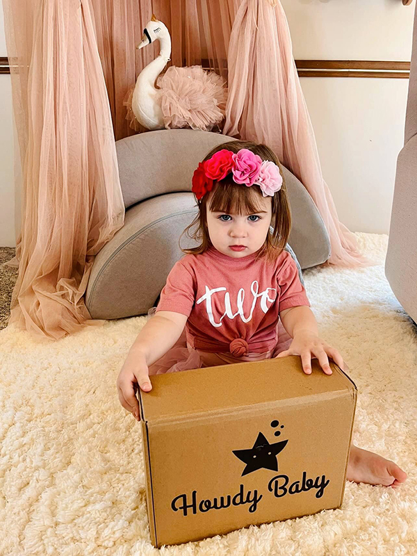 toddler girl holding the Howdy Baby maternity subscription box