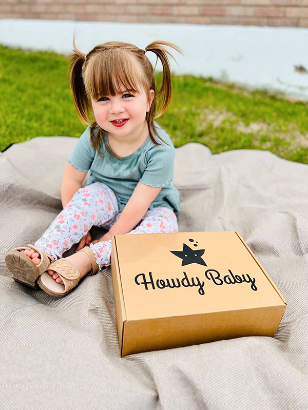 little girl sitting next to the Howdy Baby maternity subscription box