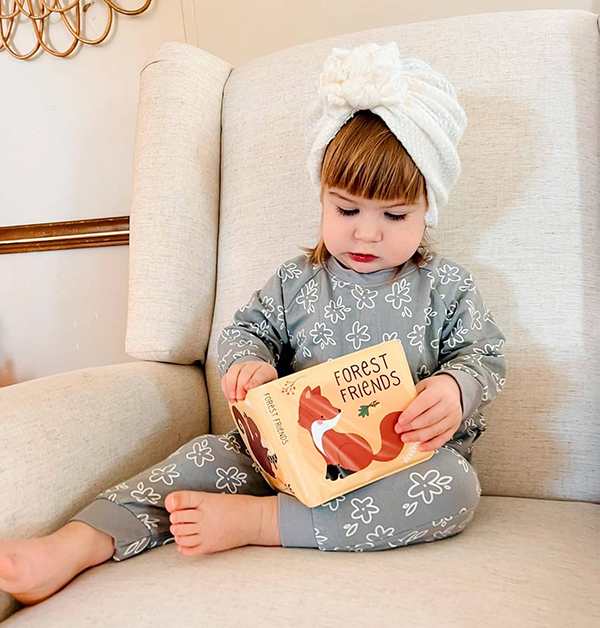 little girl holding a book from the November 2022 Howdy Baby mommy and me subscription box