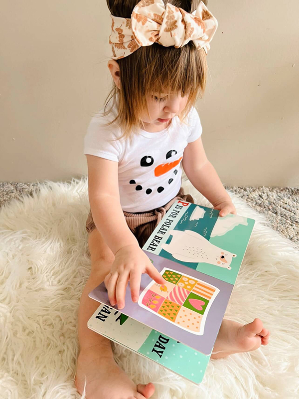 baby girl reading her monthly book from Howdy Baby mommy to be boxes