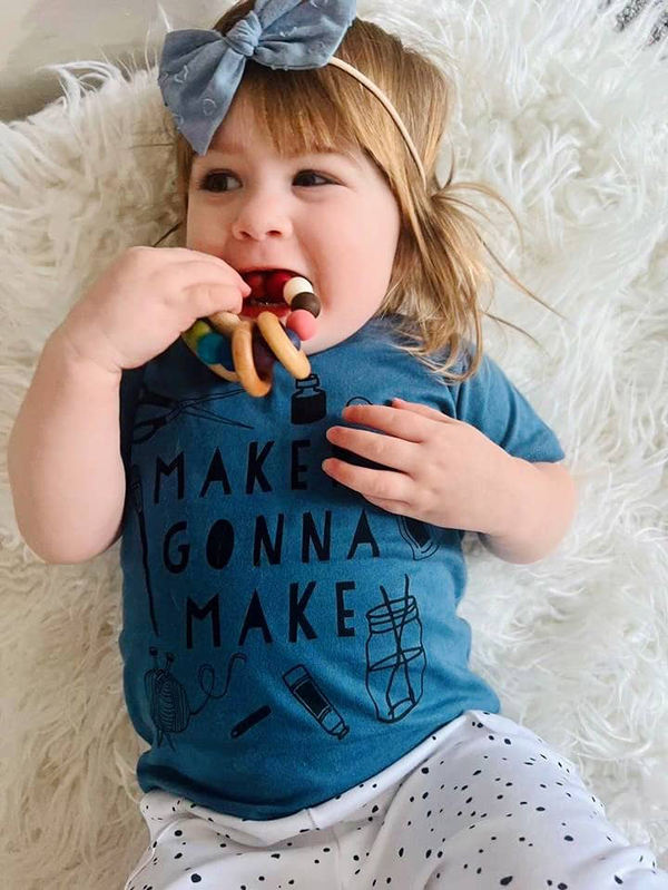 infant in white pants chewing teether from monthly subscription box for mom