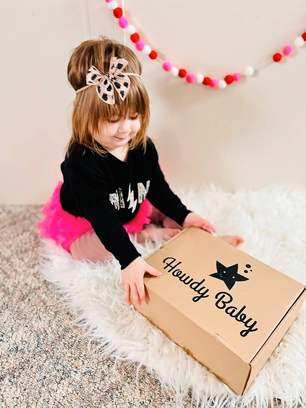 little girl unboxing her monthly Howdy Baby subscription box for moms and kids