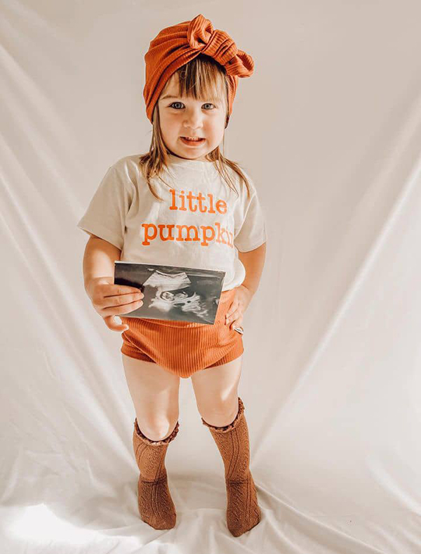 little girl wearing a pumpkin t-shirt featured in October 2023 Howdy Baby monthly subscription boxes for kids