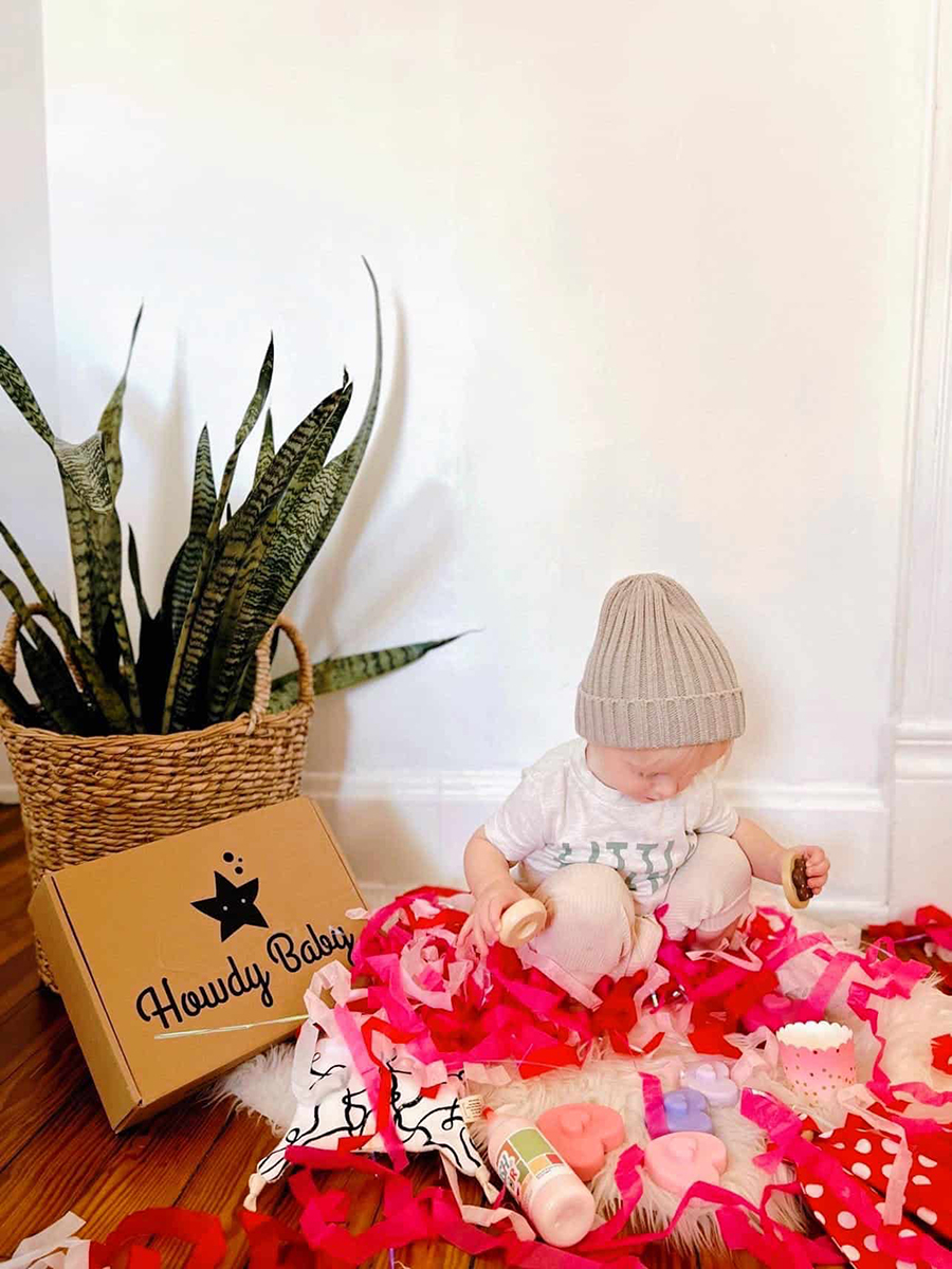 toddler boy playing with his new Howdy Baby gift box goodies