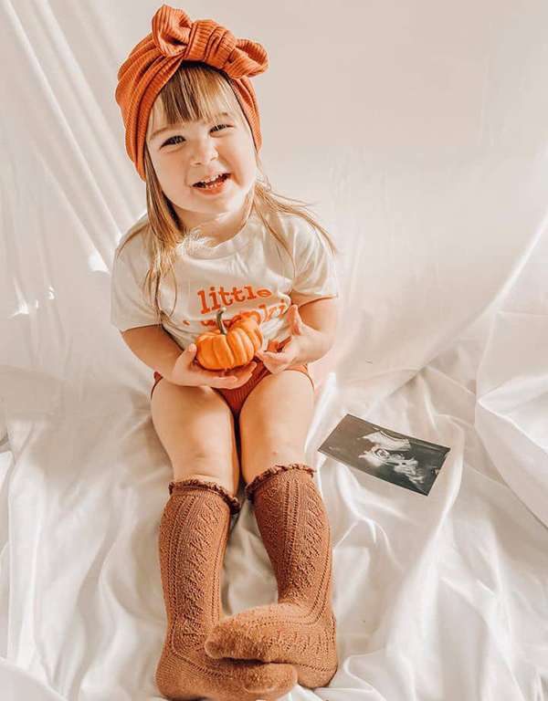 toddler girl holding a pumpkin