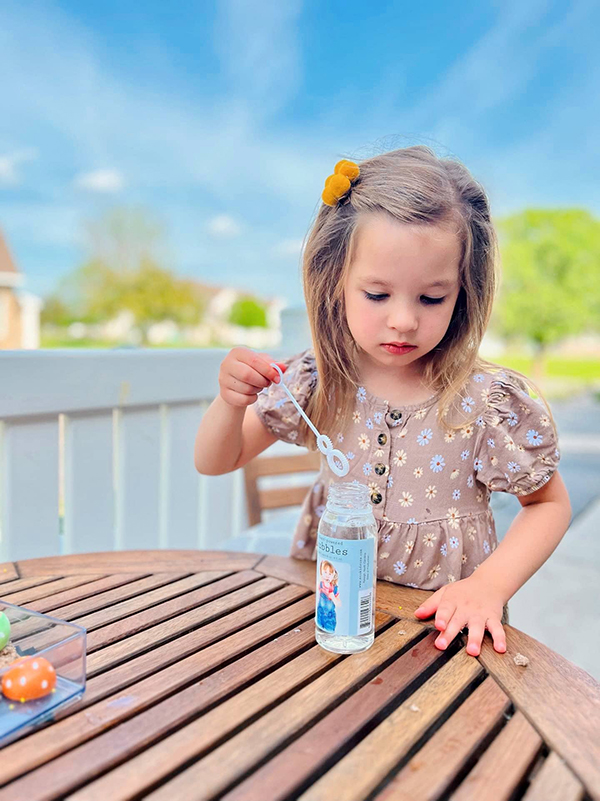 little girl playing with eco friendly plant bubbles from the May 2023 Howdy Baby subscription box for mother's day
