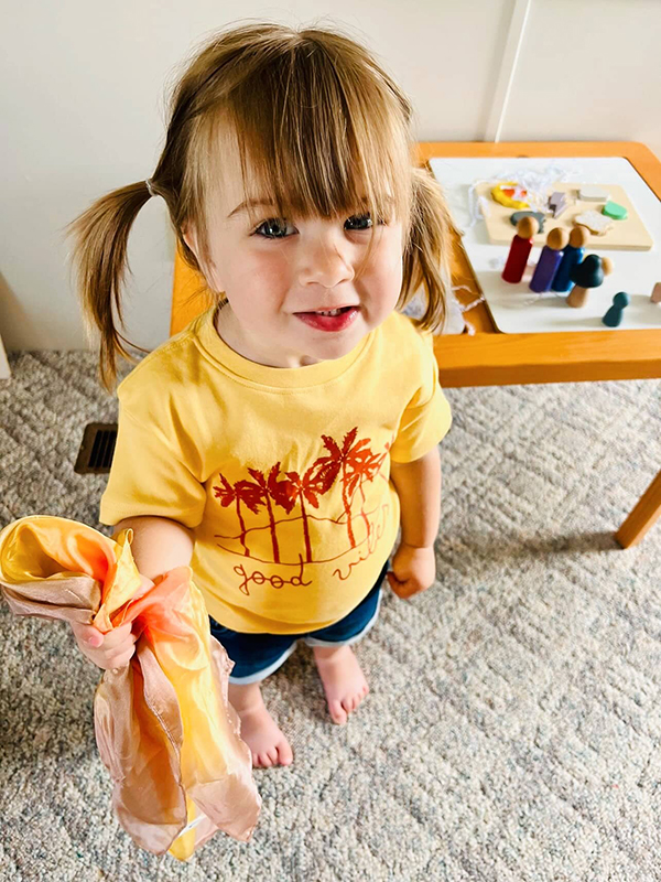toddler girl holding a yellow playsilk
