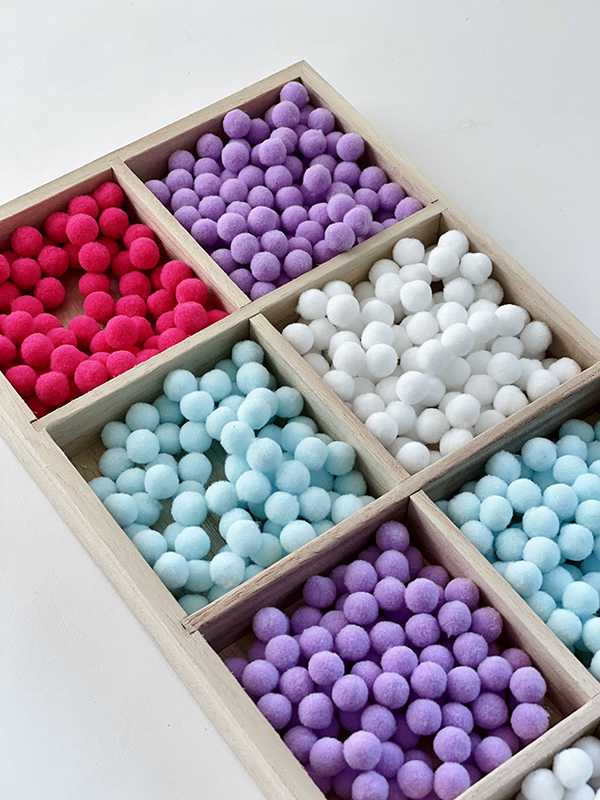 pink, blue, white, and purple pom poms sensory bin filler